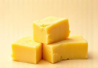 A pile of creamy-yellow Shea butter chunks, showing its natural texture